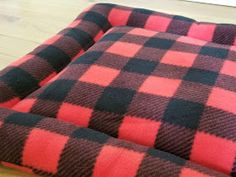 a red and black checkered dog bed on the floor