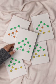 four cards with green and yellow dots on them are being held by a person's hand