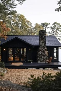 a black cabin sits on the shore of a lake