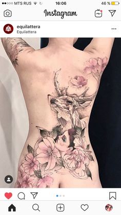 a woman's back with flowers on it and an animal tattoo in the middle