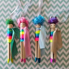 three wooden peg dolls with different colored hair and clothes hanging from them on a wall