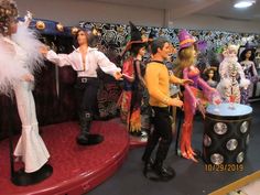 several people dressed up in costumes and hats standing around a table with dolls on it