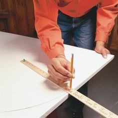 a person holding a pencil while standing next to a piece of paper on top of a table