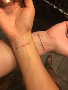 two people are holding their hands together and one has a cross tattoo on the wrist