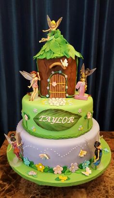 a three tiered cake decorated with tinkerbells and fairy tale characters on it