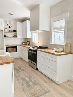 a kitchen with white cabinets and an oven in the center, along with a rug on the floor