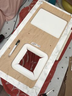 an unfinished piece of wood sitting on top of a red and white table with scissors