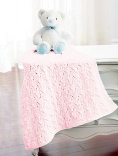 a white teddy bear sitting on top of a pink table cloth with a blue bow