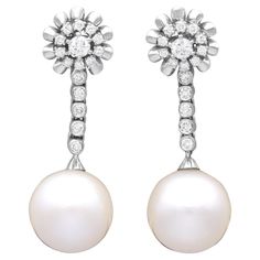 A stunning, fine and impressive pair of vintage south sea pearl, 1.30 carat diamond and 18 karat white gold earrings; part of our diverse pearl earring collections. These stunning, fine and impressive vintage pearl earrings have been crafted in 18k white gold. Each drop earring displays a stunning and large feature 14.18mm South Sea pearl terminal. The South Sea pearls suspend from an articulated linear drop composed of five individually collet set transitional modern brilliant round cut diamonds. The linear arrays are each suspended from an impressive cluster design, bearing eleven individually claw set transitional modern brilliant round cut diamonds, accented with a lobed gold border to the outer circumference. These South Sea pearl earrings with diamonds, for pierced ears, secure to th Vintage Pearl Jewelry, Earring Displays, South Sea Pearls Earrings, Cluster Design, Transitional Modern, Pearl And Diamond Earrings, Vintage Pearl, Sea Pearl, Pearl Earring