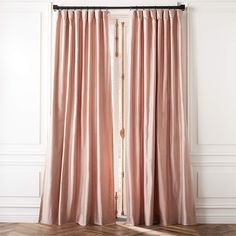 a pink curtain hanging on the side of a white wall next to a wooden floor