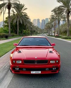 a red sports car parked on the side of a road in front of palm trees