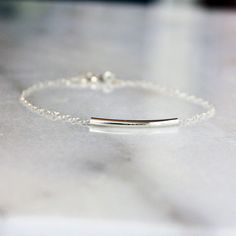 This sterling silver bracelet is the perfect minimal piece to wear alone or stack with other bracelets for an on-trend look. A subtly curved sterling silver tube glides freely across a sterling silver chain, finished with a silver spring ring clasp. Choose your ideal length from the drop-down menu. The length shown on the model is 7 inches. If you have an average size wrist, I would recommend either 6.5 or 7 inches. This piece can also be an anklet; measure your ankle for the best fit. Minimalist Adjustable Nickel-free Chain Bracelet, Sterling Silver Bracelet With Delicate Chain For Everyday, Delicate Chain Sterling Silver Bracelet For Everyday, Adjustable Silver Chain Minimalist Bracelet, Dainty Nickel-free Chain Bracelet For Everyday, Everyday Sterling Silver Bracelet With Delicate Chain, Nickel Free Minimalist Sterling Silver Chain Bracelet, Silver Minimalist Chain Bracelet With Adjustable Chain, Minimalist Sterling Silver Nickel-free Chain Bracelet