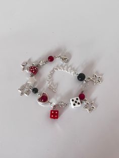 a stunning handmade charm bracelet. decorated with red, black & white beads, silver hanging star charms, hearts, and dice. adjustable chain to fit any wrist. can be personalised with different colours & charms (prices may vary). perfect for the 'stargirl' aesthetic! Red Aesthetic Bracelet, Red And Black Bracelets Beads, Red Charm Bracelet, White Charm Bracelet With Star Charm As Gift, Adjustable Metal Charm Bracelet With Star Charm, Metal Star Charm Bracelet Gift, Handmade Adjustable Metal Charms, Red Dangle Charm Bracelet As Gift, Red Dangle Charm Bracelet For Gift