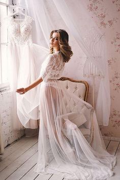 a woman sitting on a chair in front of a window wearing a wedding dress and veil