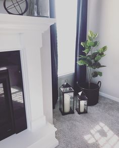 two candles sitting next to each other on the floor in front of a fire place