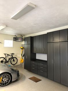 a car is parked in a garage with two bikes on the wall and several cabinets