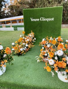 several white vases filled with orange and white flowers on top of a grass covered field