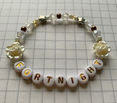 a bracelet with the word birth spelled out in gold and white beads on a table