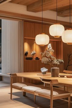 a dining room table and chairs with lights hanging from the ceiling above it, along with two vases on either side of the table