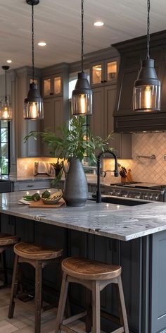 a kitchen island with stools and lights above it