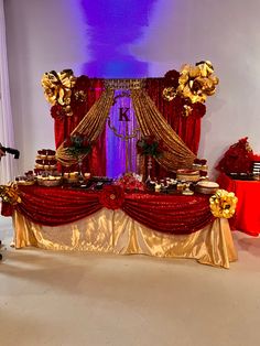 a red and gold dessert table set up for a party or event with decorations on it