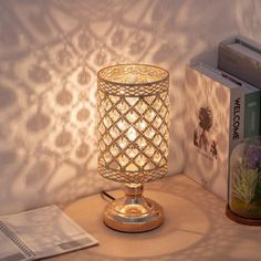 a lamp sitting on top of a wooden table next to a book and some books