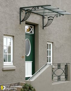 a green door and some steps in front of a gray house with white trim on it