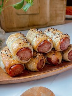 several sausages wrapped in bread on a wooden platter