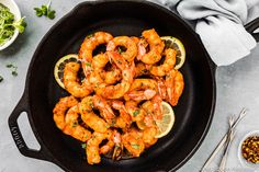 cooked shrimp in a skillet with lemon wedges and parsley on the side