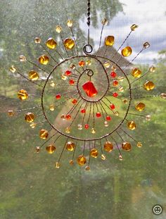 a sun catcher made out of glass and beads hanging from the side of a window