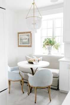 a living room with white furniture and a chandelier hanging over the dining table