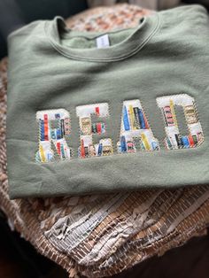 a green shirt with the word read on it and some books in front of it