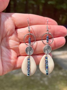 These cowrie shell beaded earrings are gorgeous. They look good with any outfit. They are one of kind and unique.  They are delicately designed with stainless steel components, cowrie shells, spiral beads, and accented with blue miyuki Picasso beads, with french hook ear posts These earrings come to you in a white box ready for gift giving Please note colors may vary from picture, and it is advised to not wear in water or get wet. Your satisfaction is my first priority. If you are not happy with Bohemian Shell Earrings For Jewelry Making, Beach Teardrop Beaded Earrings For Pierced Ears, Teardrop Beaded Earrings For Beach, Bohemian Shell Earrings Nickel Free, Nickel Free Shell Bohemian Earrings, Beach Wire Wrapped Beaded Drop Earrings, Bohemian Shell Beaded Earrings, Bohemian Nickel-free Shell Earrings, Spiral Wire Wrapped Jewelry For Beach