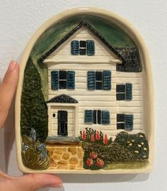 a hand holding up a small ceramic house