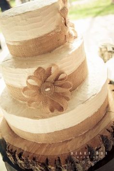 a three tiered cake with burlap flowers on top