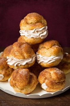 a pile of pastries sitting on top of a white plate next to a purple cloth