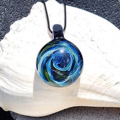 This stunning Galaxy Pendant is handmade with borosilicate glass, making each piece truly unique, like a work of art. Crafted with care, this one-of-a-kind pendant features a circular design inside, created with pure silver and gold fuming. When heated, these metals work their magic, transforming into beautiful colors that shift from white to shades of blue, with touches of orange and green, creating a galaxy-like effect.                               Peace, love, and pendants, baby! ✌️💚🌊 The Multicolor Recycled Glass Jewelry As A Gift, Multicolor Recycled Glass Jewelry For Gifts, Murano Glass Round Jewelry For Gift, Round Recycled Glass Necklaces For Gifts, Iridescent Glass Jewelry As Gift, Iridescent Glass Jewelry Gift, Artistic Round Glass Jewelry, Modern Handmade Murano Glass Jewelry, Iridescent Glass Jewelry For Gifts