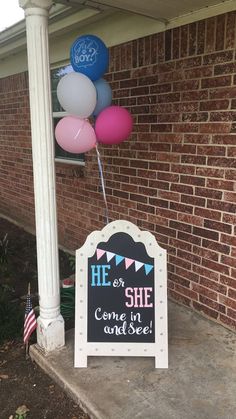 a sign that says he is she and balloons