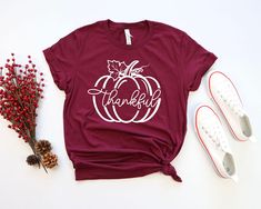 a t - shirt with the words thanks on it next to red berries and white sneakers