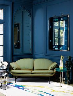 a living room with blue walls and furniture in the corner, including a couch and coffee table