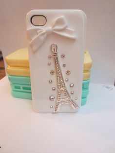 a cell phone case with a bow and eiffel tower in the back on top of stack of plates