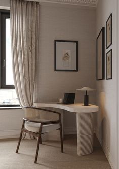 a room with a desk, chair and pictures hanging on the wall next to it