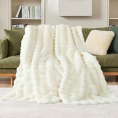 a large white fur blanket sitting on top of a couch next to a book shelf