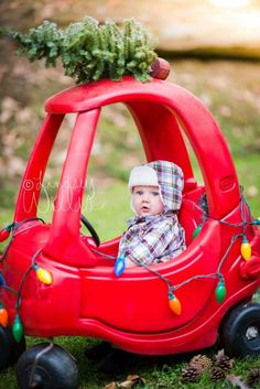 a baby in a red car with christmas lights