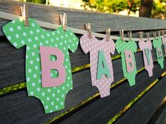 baby clothes are hung on the clothesline to spell out their name, and it is decorated with polka dots