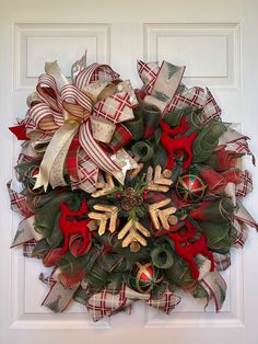 a christmas wreath is hung on the front door with ribbons and decorations around it,