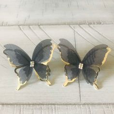 two black and gold butterflies sitting on top of a white floor next to each other