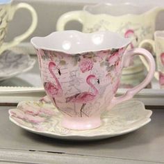 a pink and white tea cup sitting on top of a saucer next to a plate