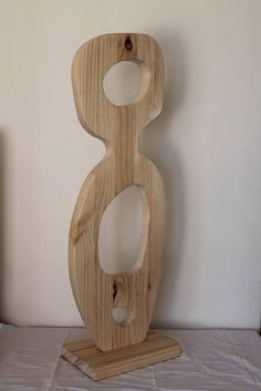 a wooden sculpture sitting on top of a table next to a white wall and floor