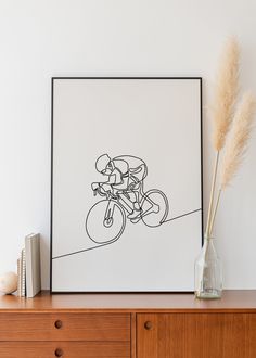 a black and white drawing of a man riding a bike on a wall above a dresser